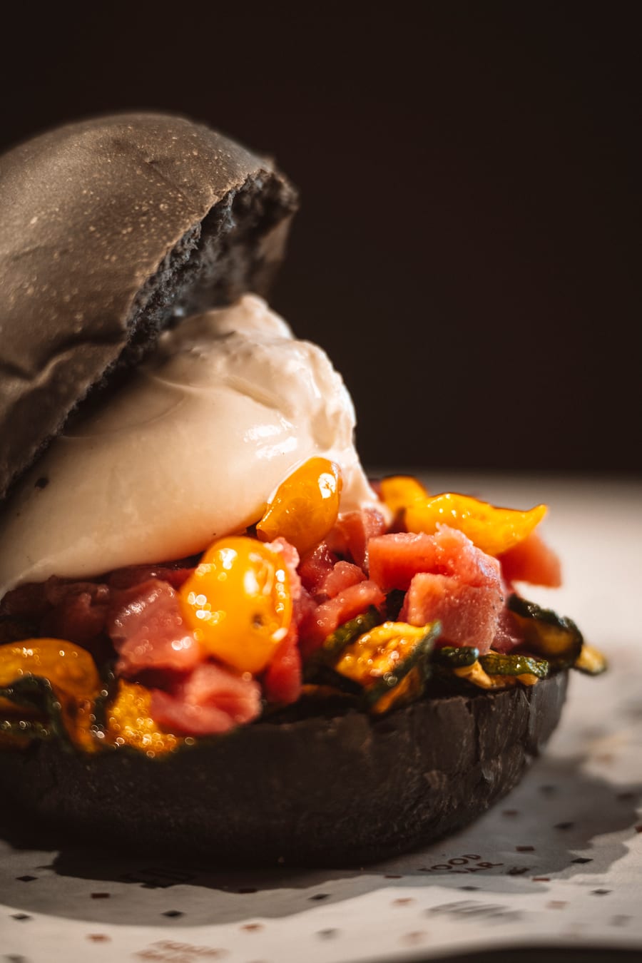 Il panino di pane nero aperto sulla tartare di tonno, la burrata e i pomodorini gialli