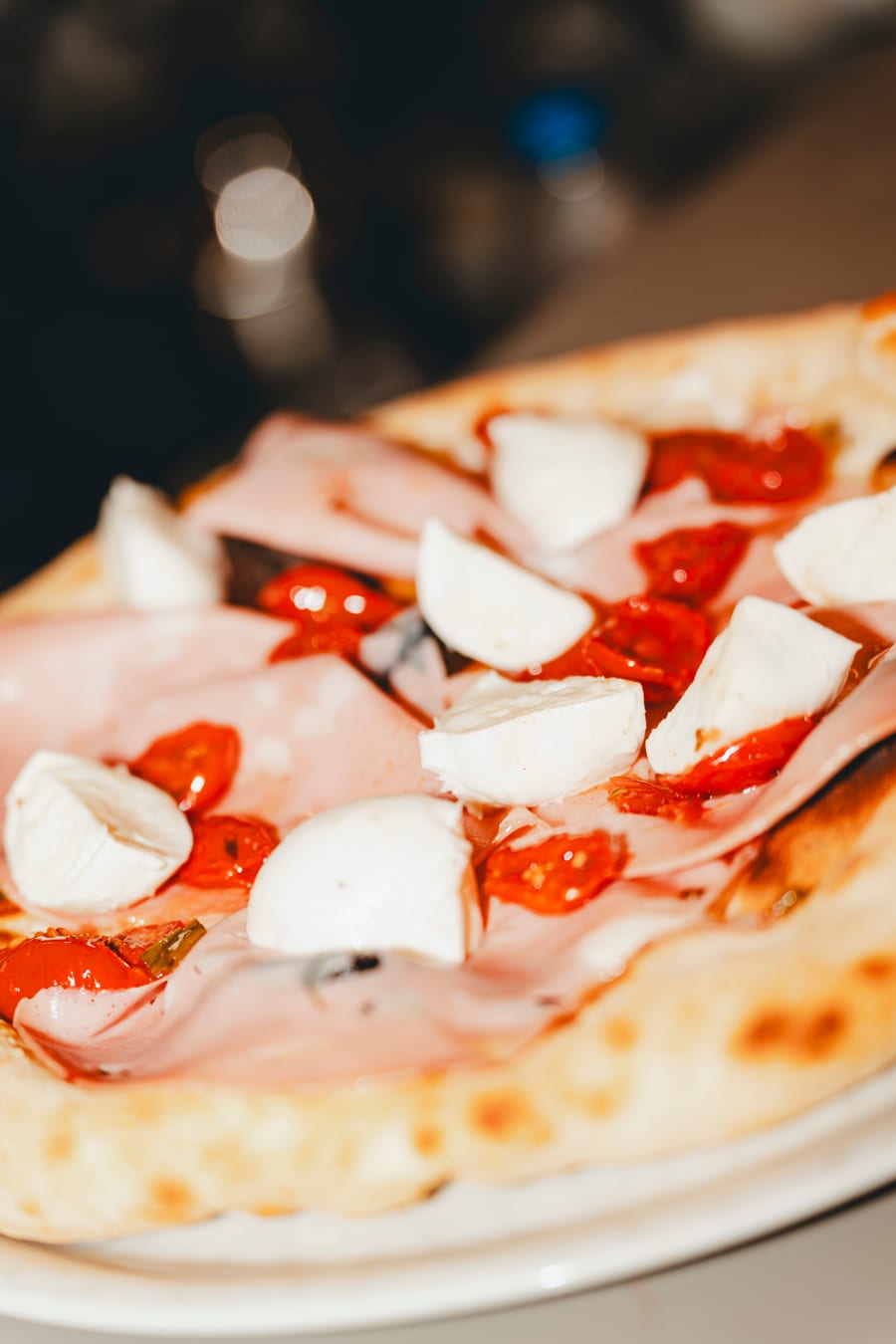Da vicino, una pizza con la mortadella, i bocconcini di bufala e i pomodorini