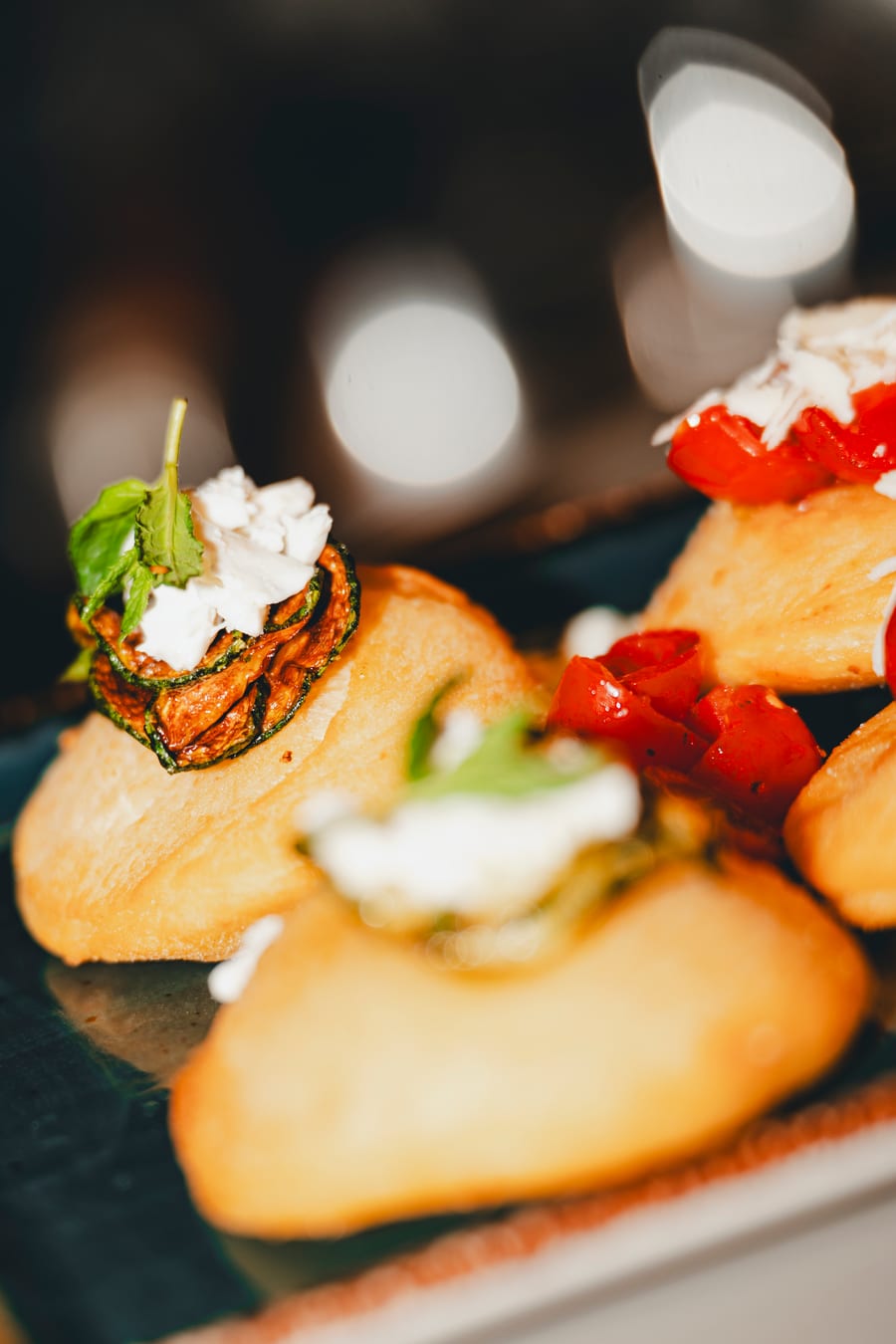 Pizzette fritte con la stracciatella, i pomodorini e una foglia di basilico, sul banco