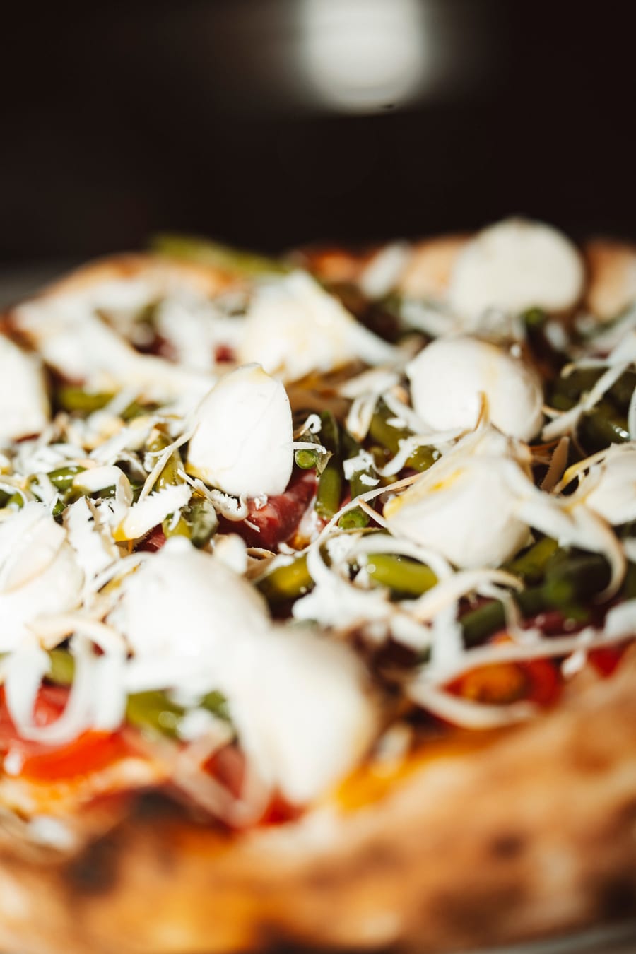 Da vicino, una pizza con i fagiolini, la bufala e il formaggio grattugiato