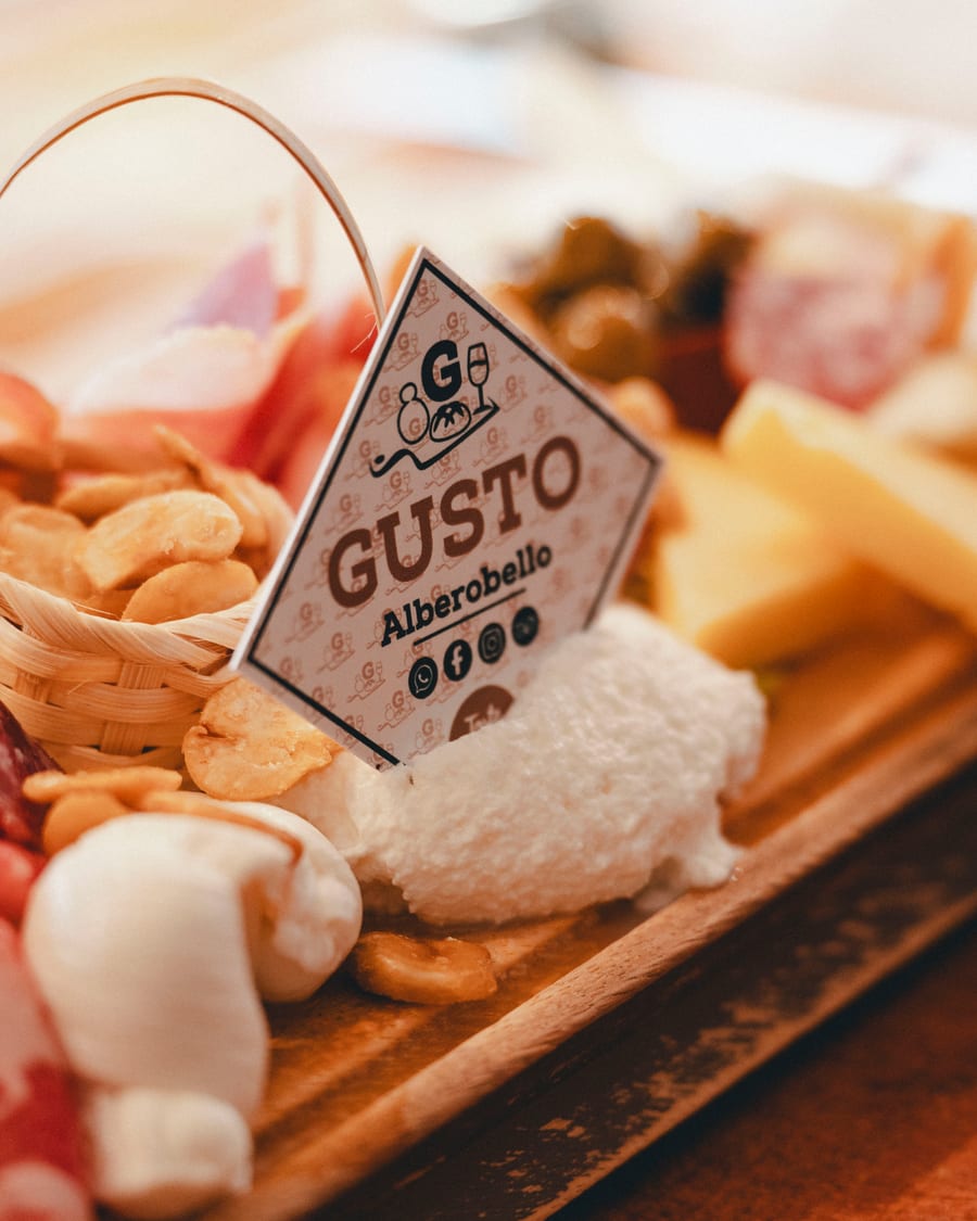 Il cartoncino «Gusto Alberobello» piantato nel tagliere, fra taralli, stracciatella e salumi