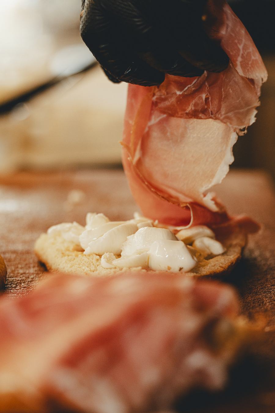 Una fetta di prosciutto crudo posata su una bruschetta con la mozzarella, sul tagliere