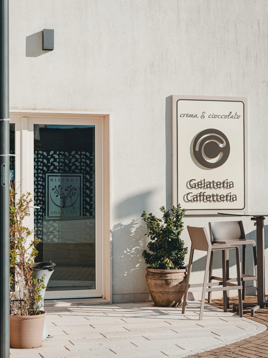 L’ingresso del locale al sole, con l’insegna «Gelateria Caffetteria» accanto alla porta a vetri
