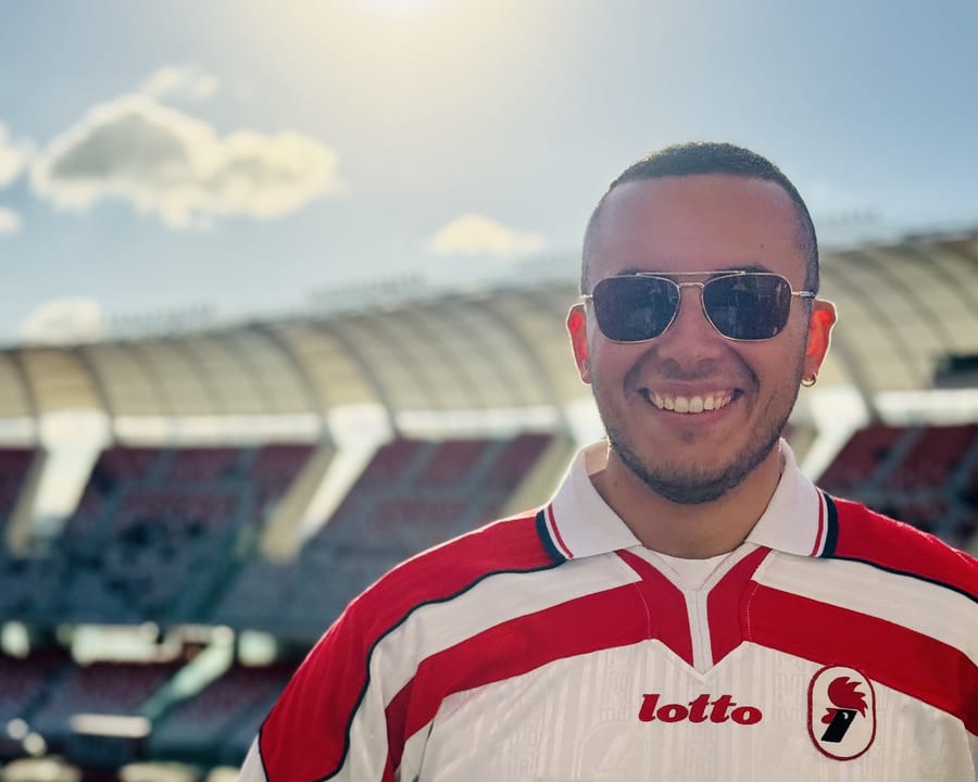 Alessandro Lupelli sorridente in maglia del Bari, sugli spalti vuoti dello stadio San Nicola